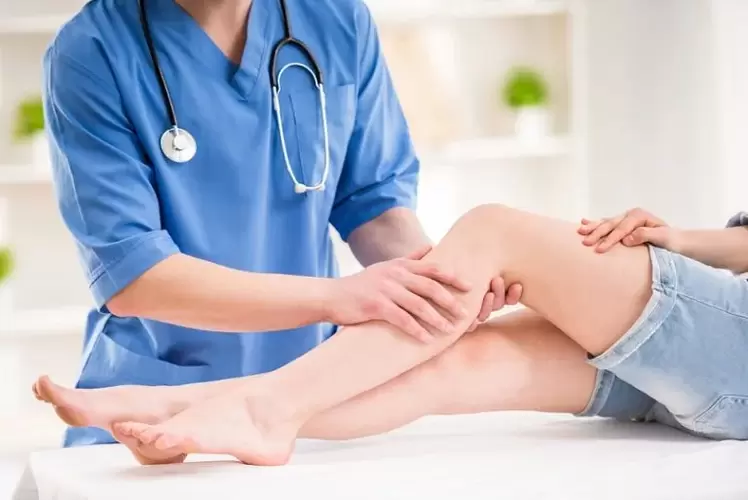 lékař zkoumá nohu s křečovými žilami